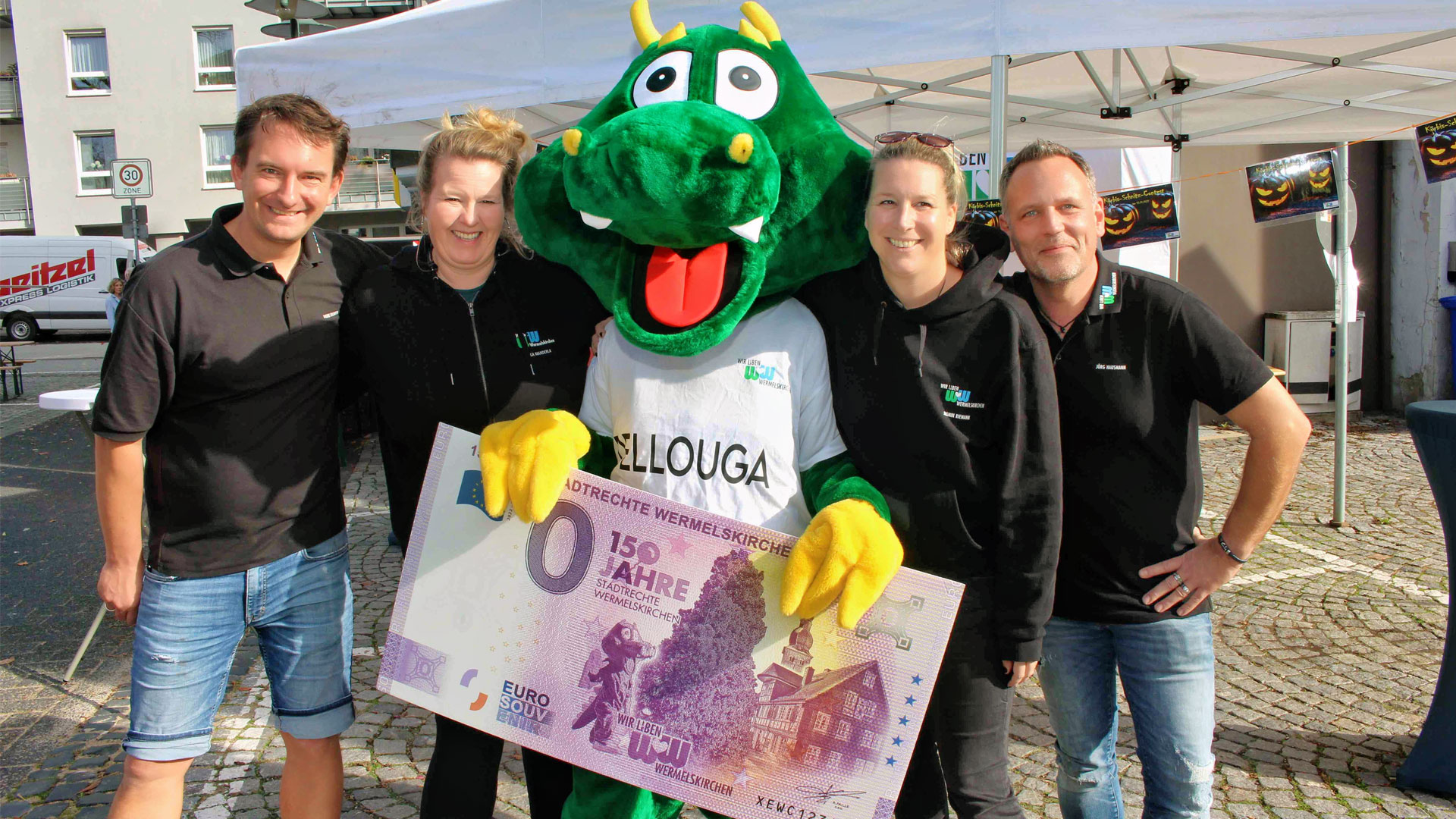 Team mit Maskottchen Dellouga präsentiert den 0-Euro-Souvenirschein