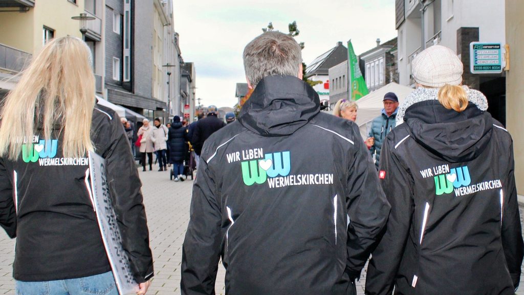 Helfer in WiW-Jacken von hinten in der Fußgängerzone