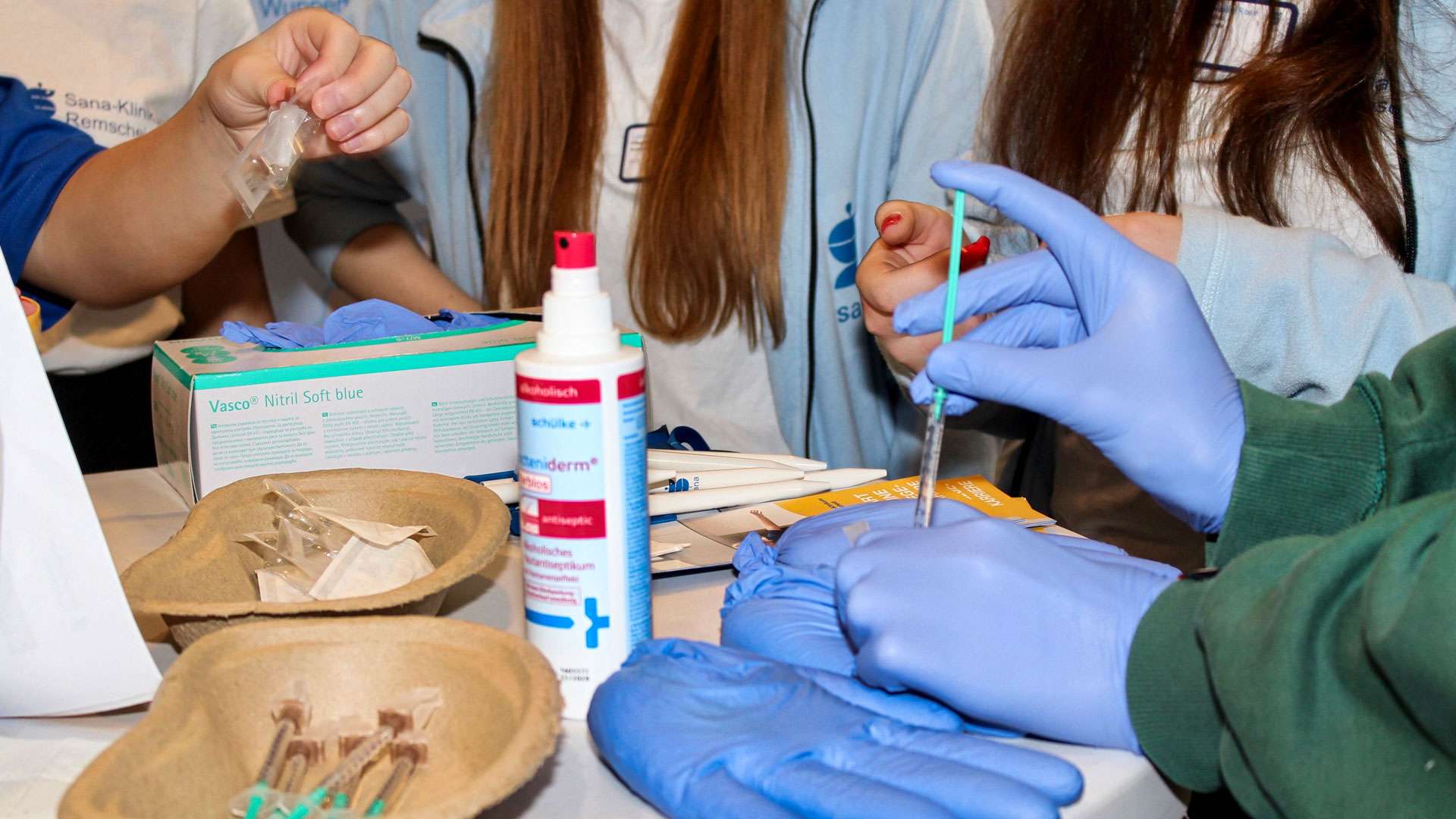 Mitmachaktion mit Handschuhen und Pipette an einem Gesundheitsstand bei Connect 2025