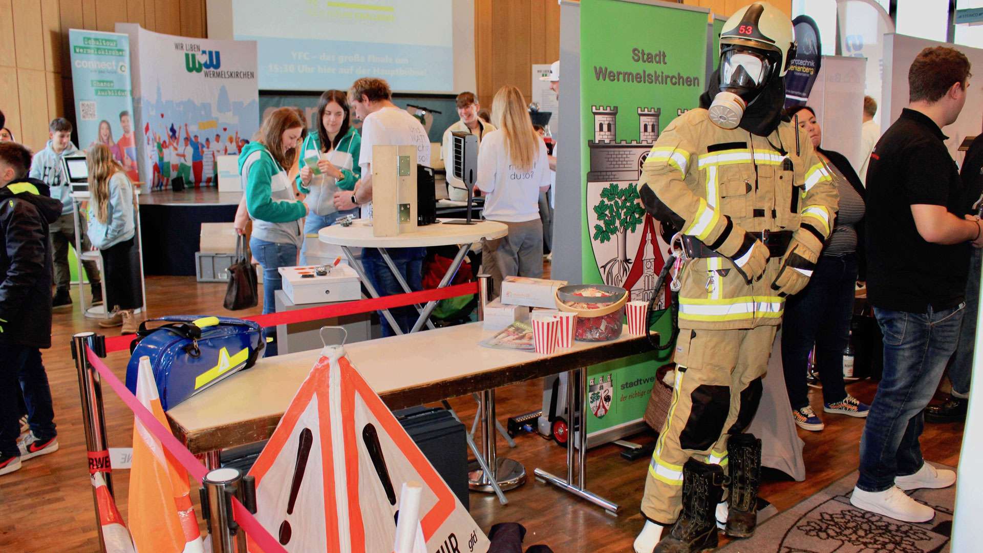 Messehalle mit Feuerwehr-Schutzanzug und Ständen bei Connect 2025
