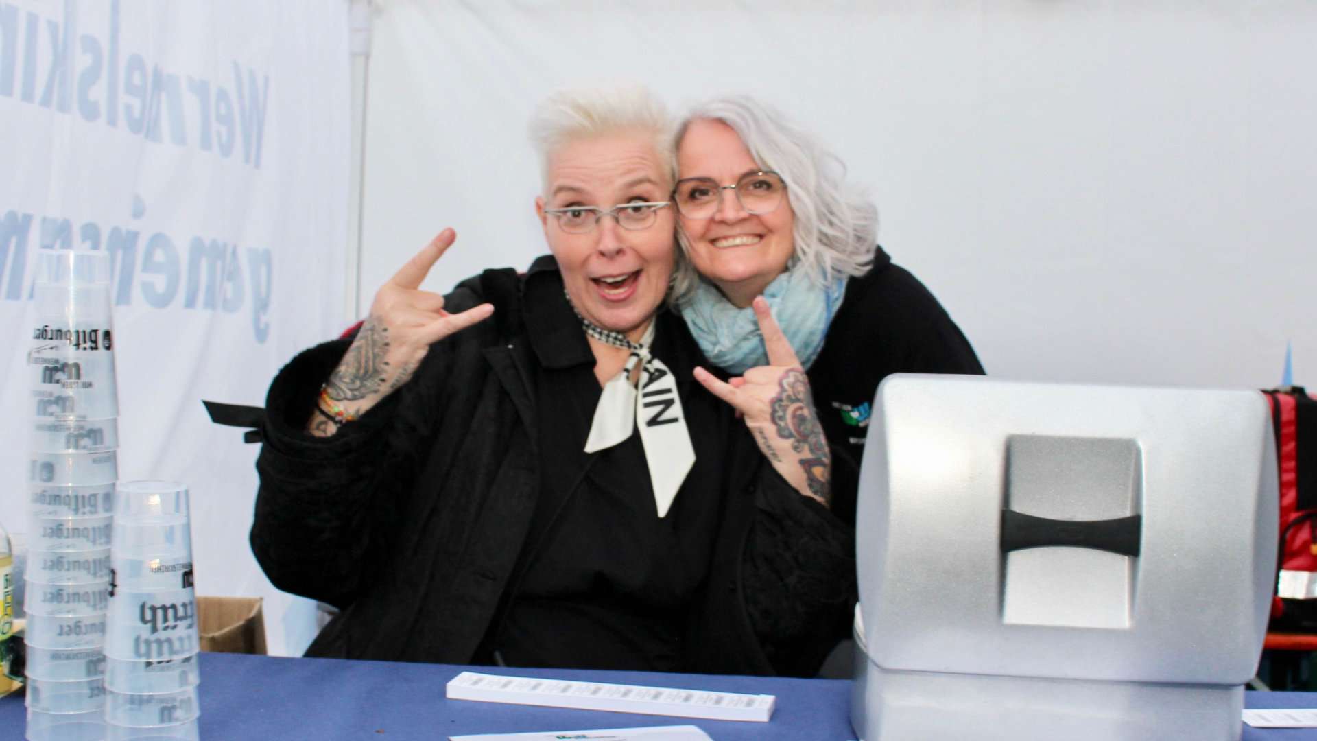 Zwei Frauen mit Rock-Geste am Stand bei Rock am Markt