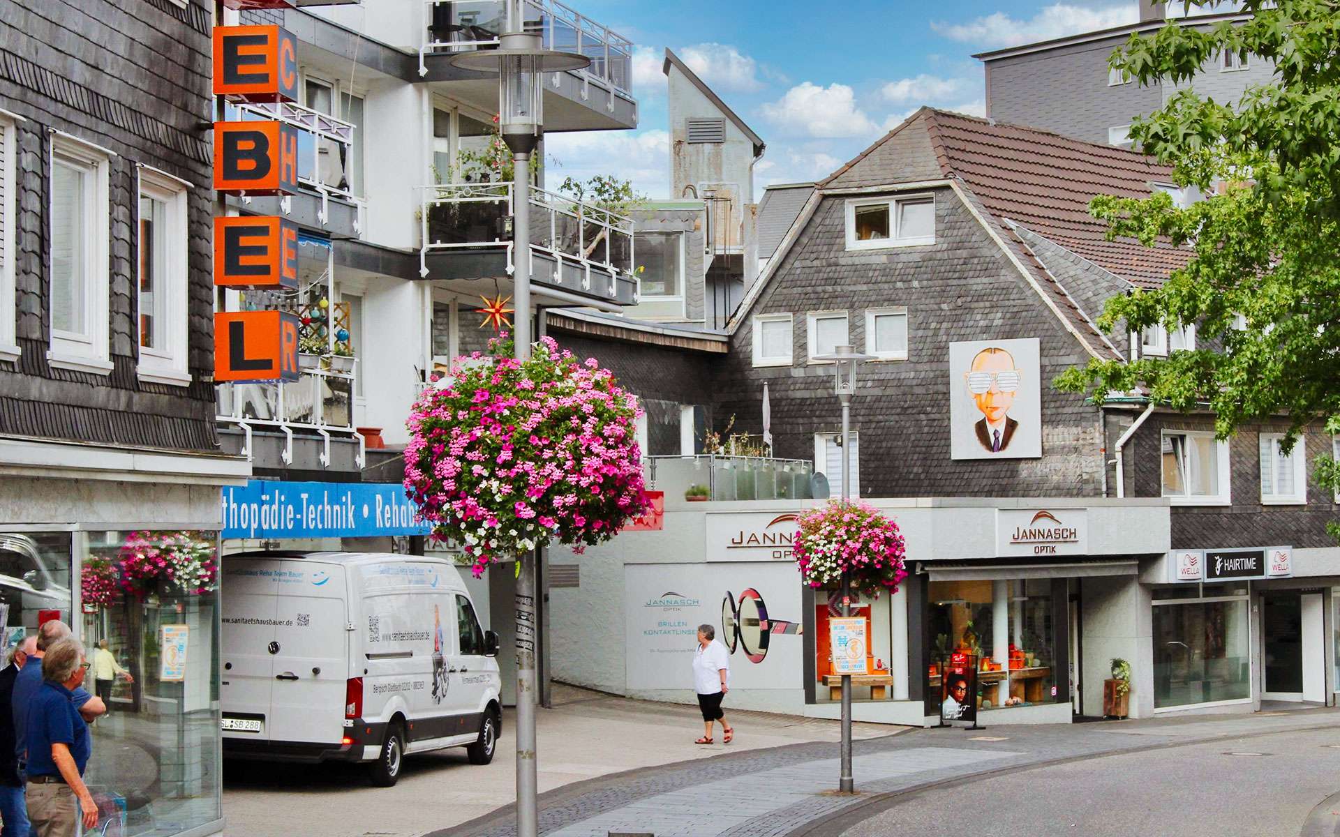 Blumenampeln an Laternen in einer Einkaufsstraße