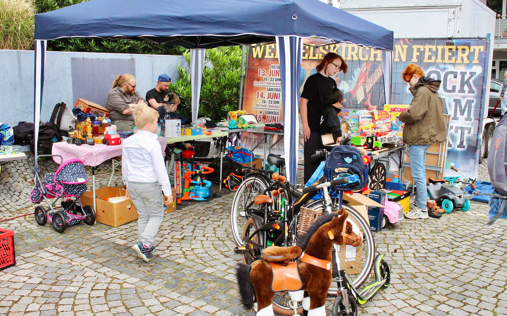 Trödelstand mit Spielsachen und Kinderrädern beim Fest