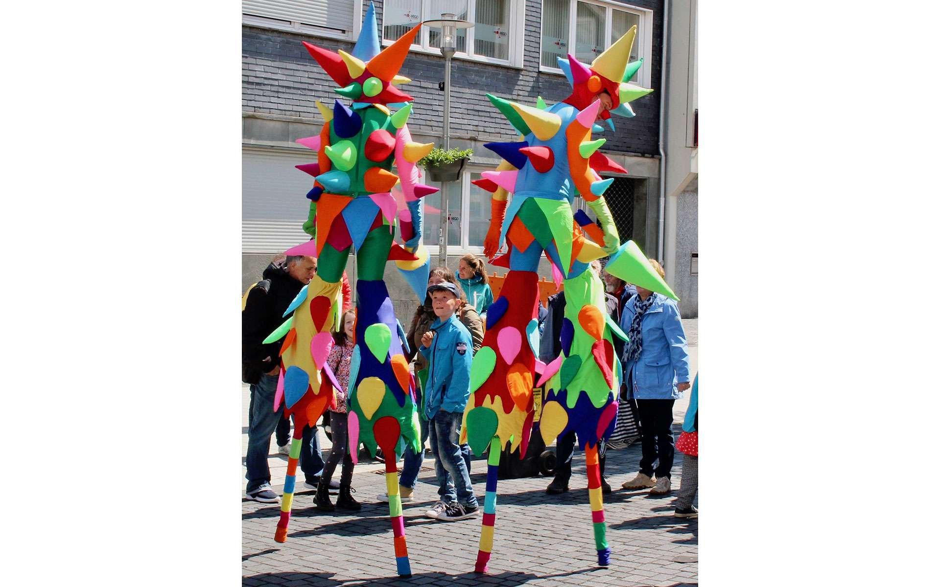 Bunte Stelzenläufer in Fantasiekostümen beim Fest