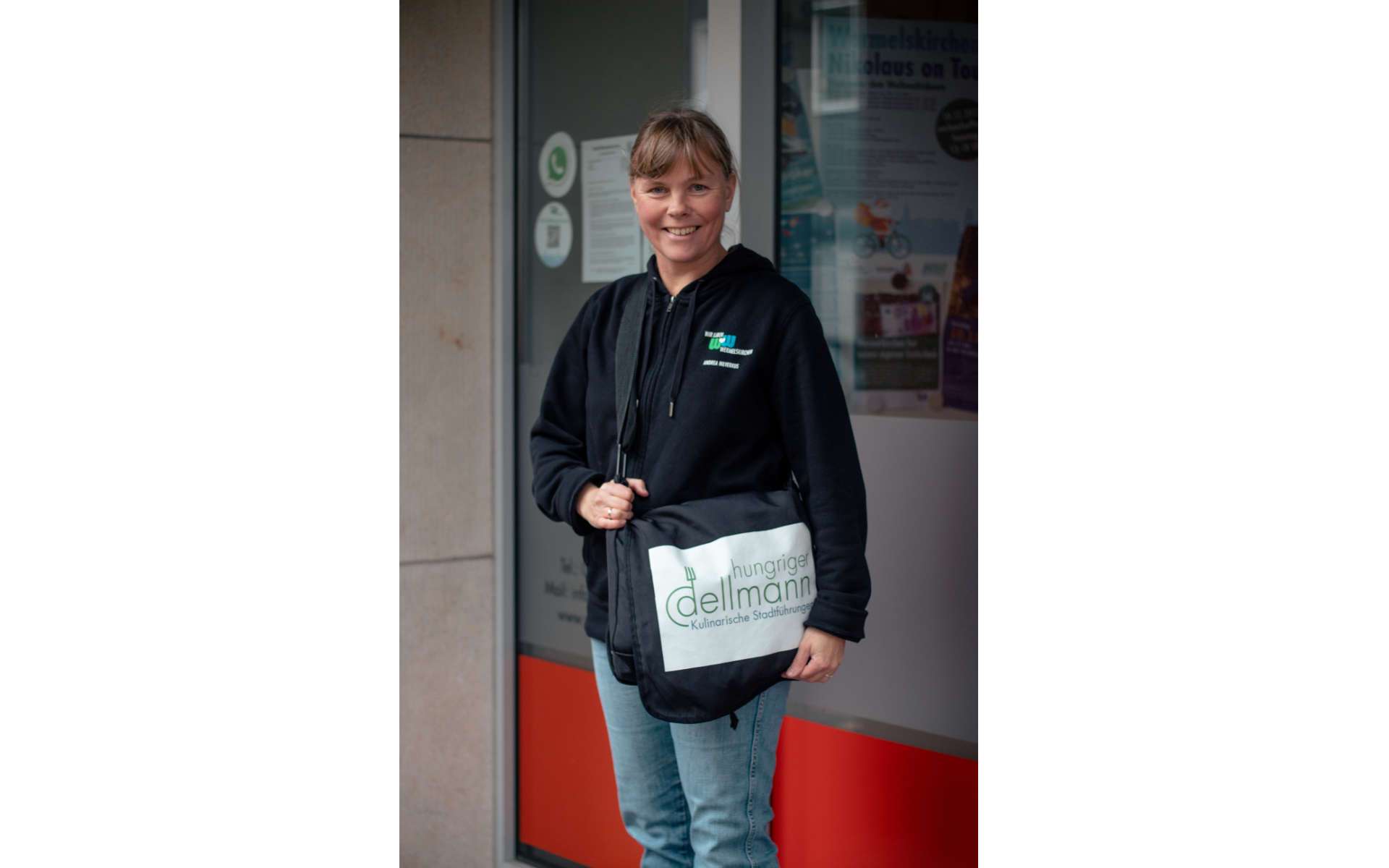Stadtführerin mit Tasche vor einem Geschäft