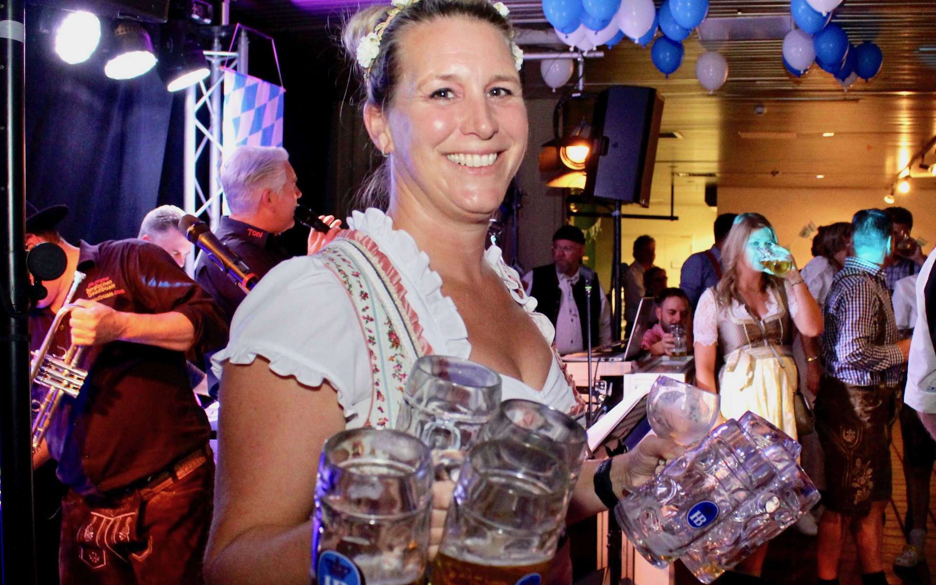 Bedienung im Dirndl trägt Bierkrüge beim Oktoberfest