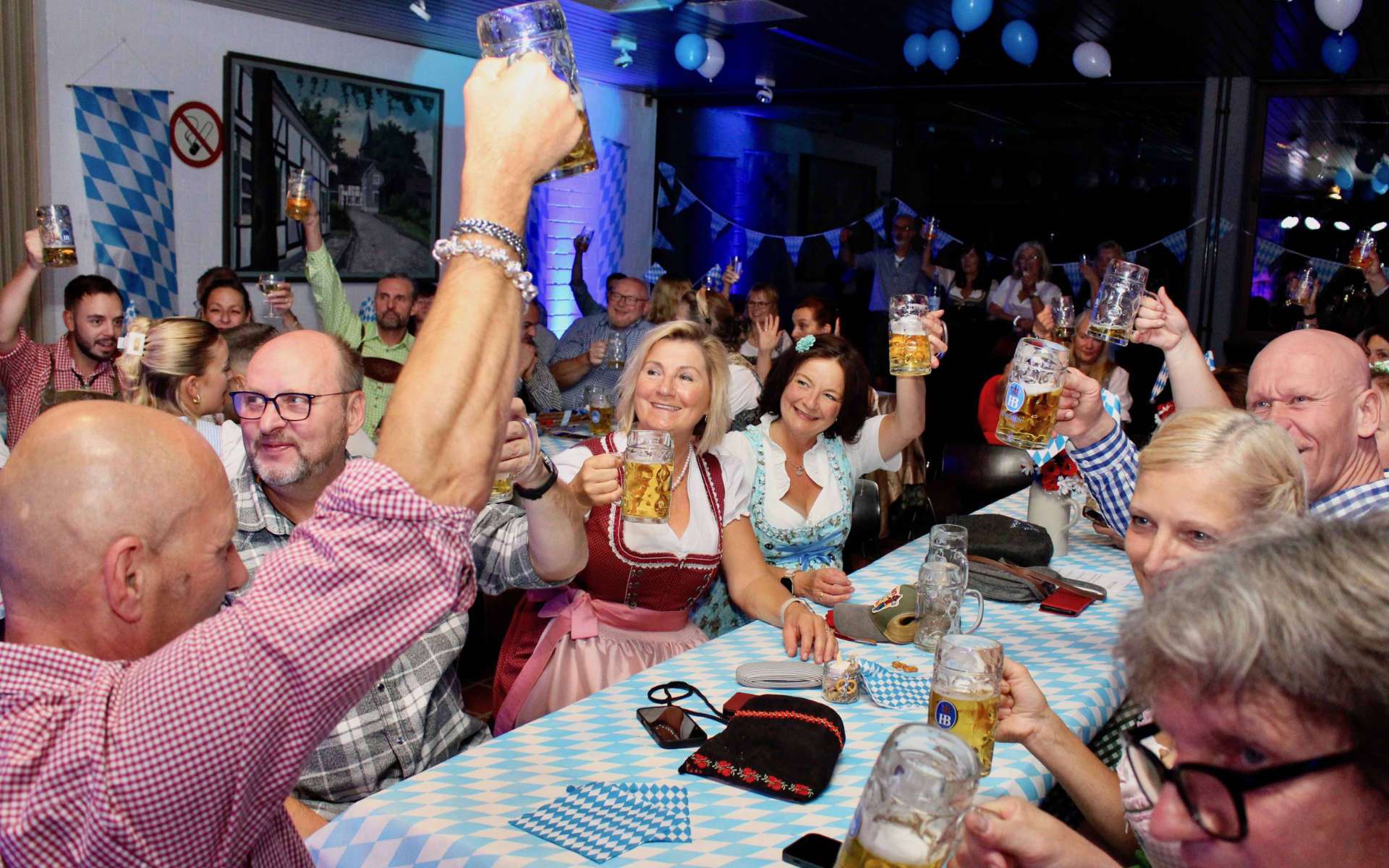 Gäste stoßen mit Bierkrügen an beim Oktoberfest