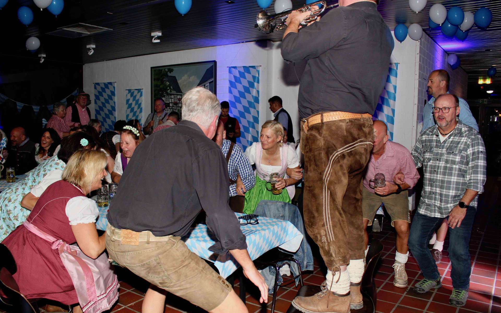 Gäste in Lederhosen und Dirndl tanzen beim Oktoberfest