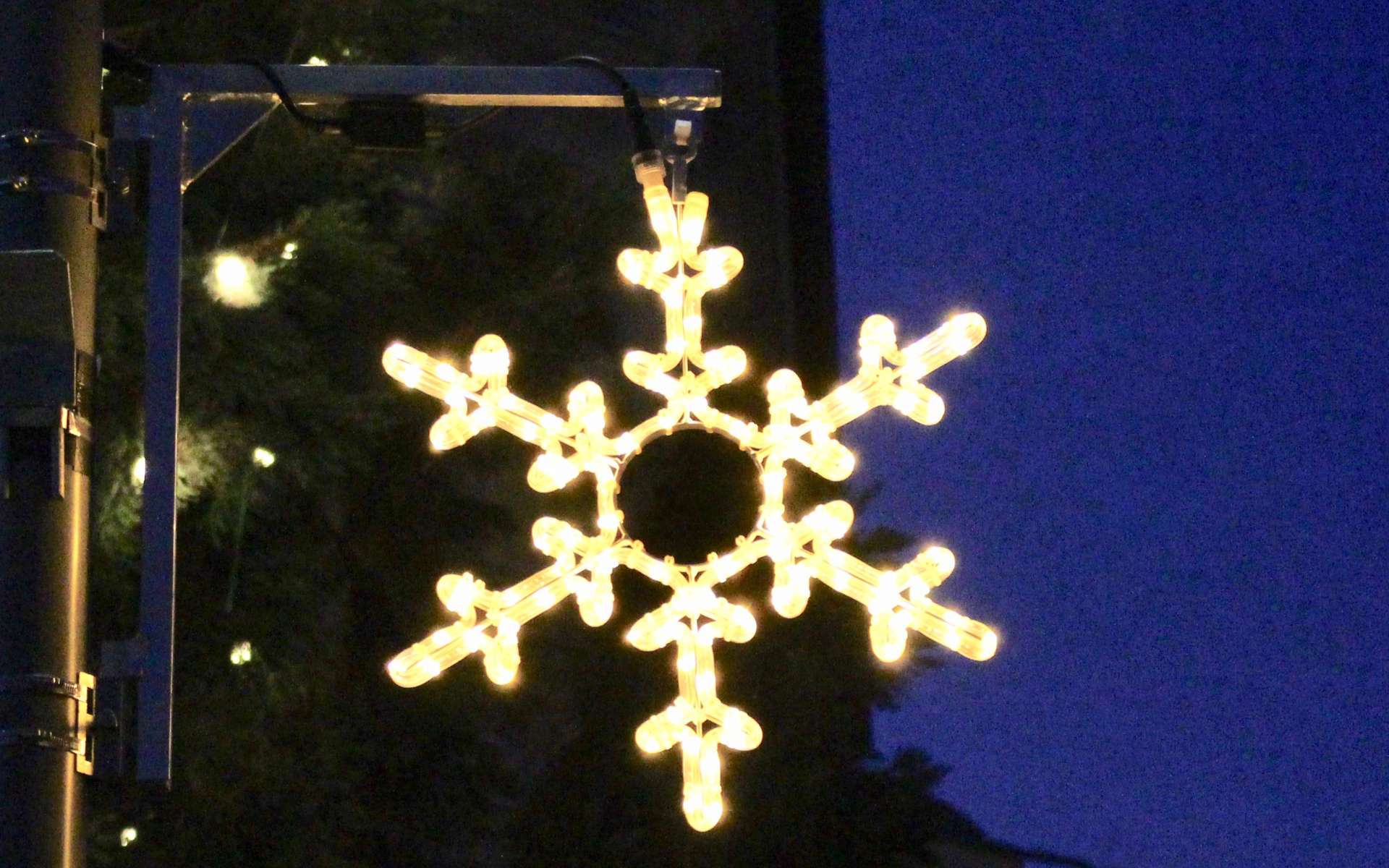 Leuchtende Schneeflocke an einer Laterne am Abend