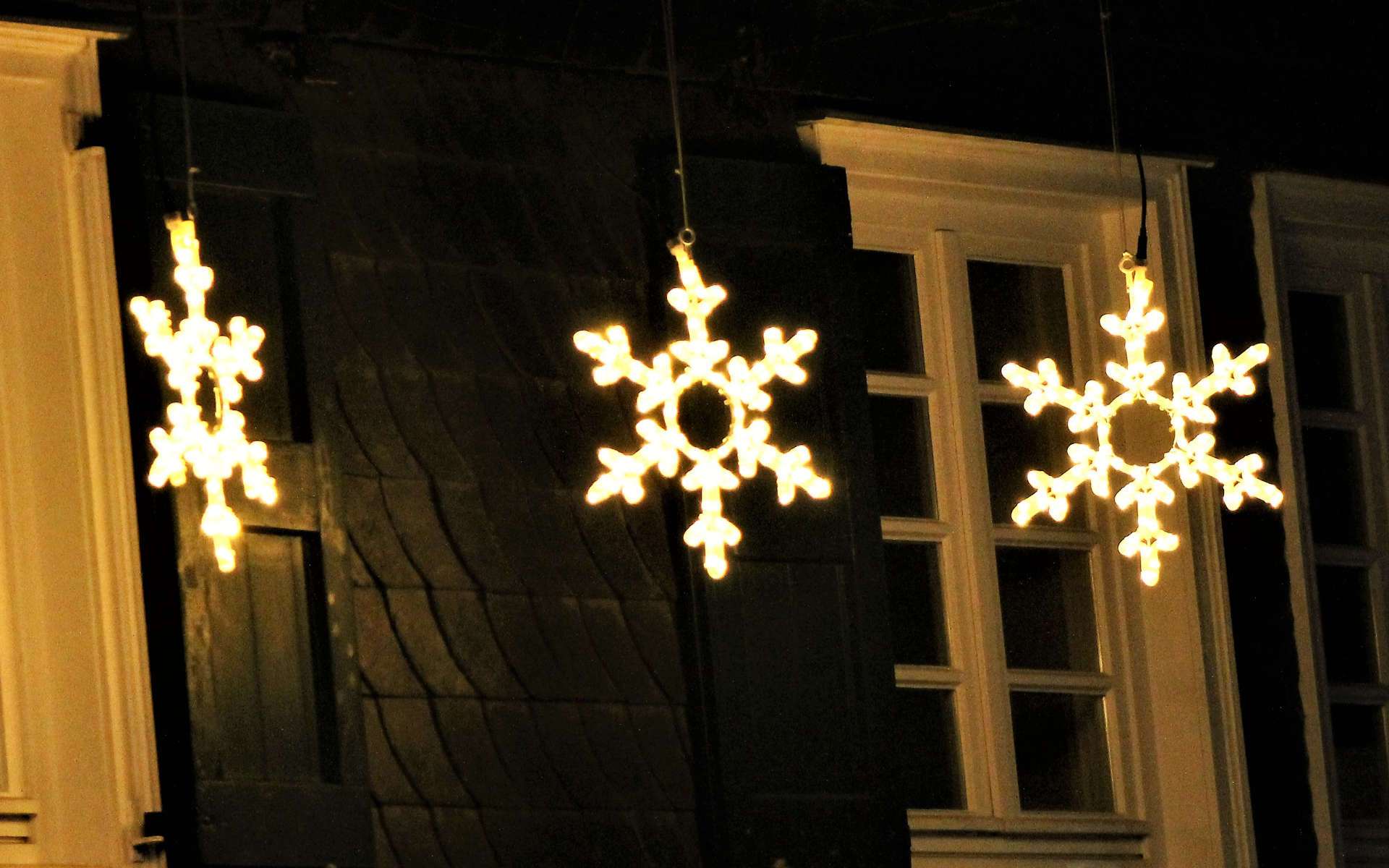 Leuchtende Schneeflocken an einer Hausfassade